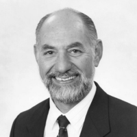 An older man with glasses smiling